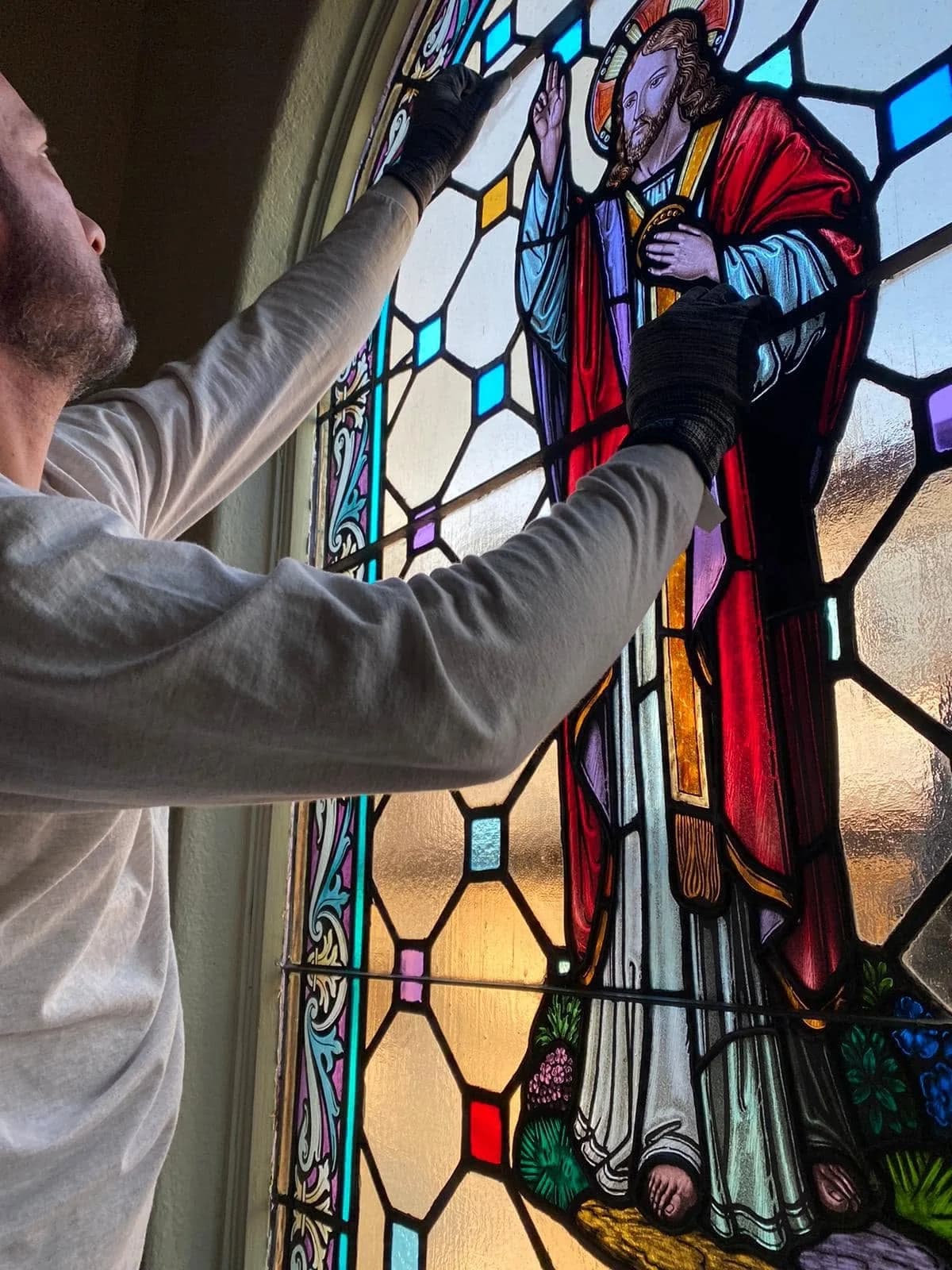 Craftsman working on a stained glass repair with careful hand placement